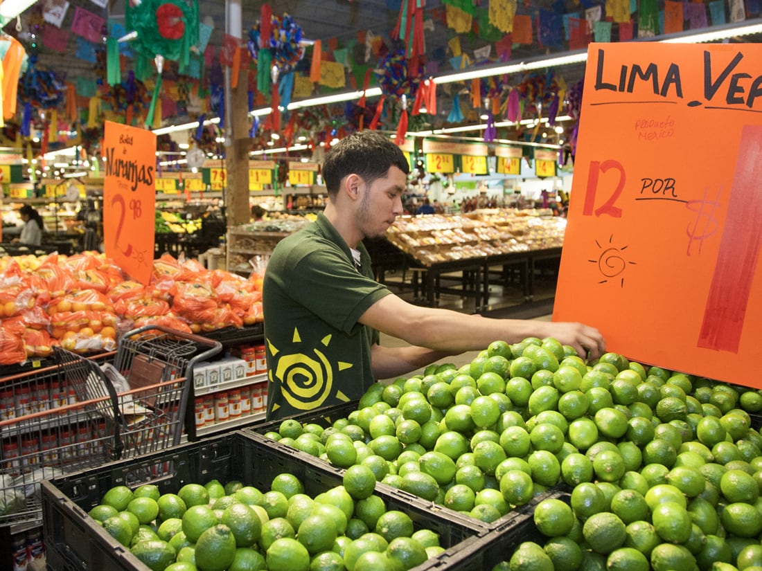 Employee working the produce section at an HEB grocery store.