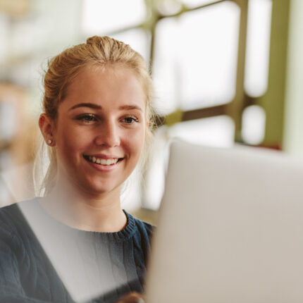 Beautiful young female student using laptop in classroom. Girl studying with laptop in university class.