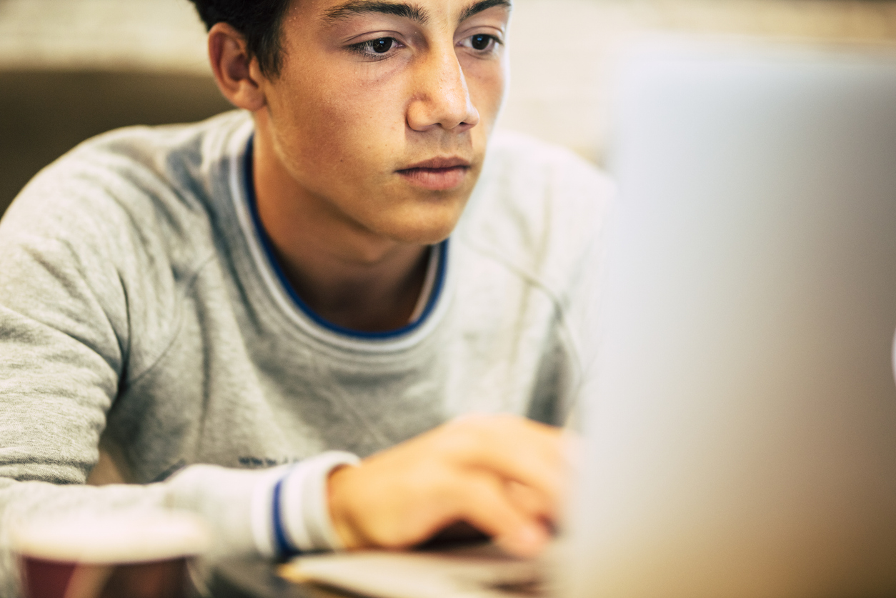 Portrait of teenager at home using his laptop for watching videos or playing games - one man working at the office with his computer