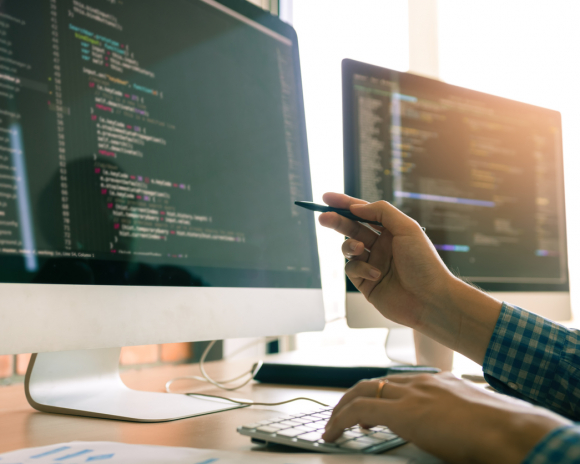 Developing programming working in a software engineers code tech applications on desk in office room.