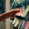 Hand, business and sticky note with planning, ideas and creativity for novel and schedule for writing.