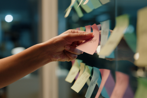 Hand, business and sticky note with planning, ideas and creativity for novel and schedule for writing.
