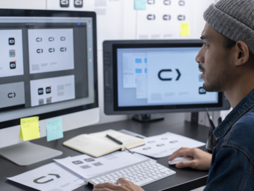 Young Asian graphic designer working in his studio office. Sketching on paper and using computer for work.