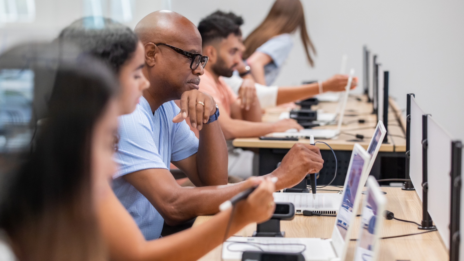 A mix of people are attending a class together in a computer lab.