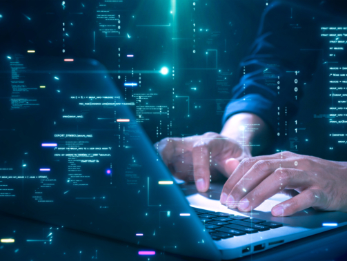 Close-up of hands typing on a laptop with glowing programming code and binary graphics, symbolizing cybersecurity technology coding or software development.