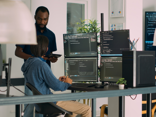 Diverse programmers collaborating on coding project compiling algorithm for new cloud computing user interface on computer monitors. Team of software engineers brainstorming ideas.