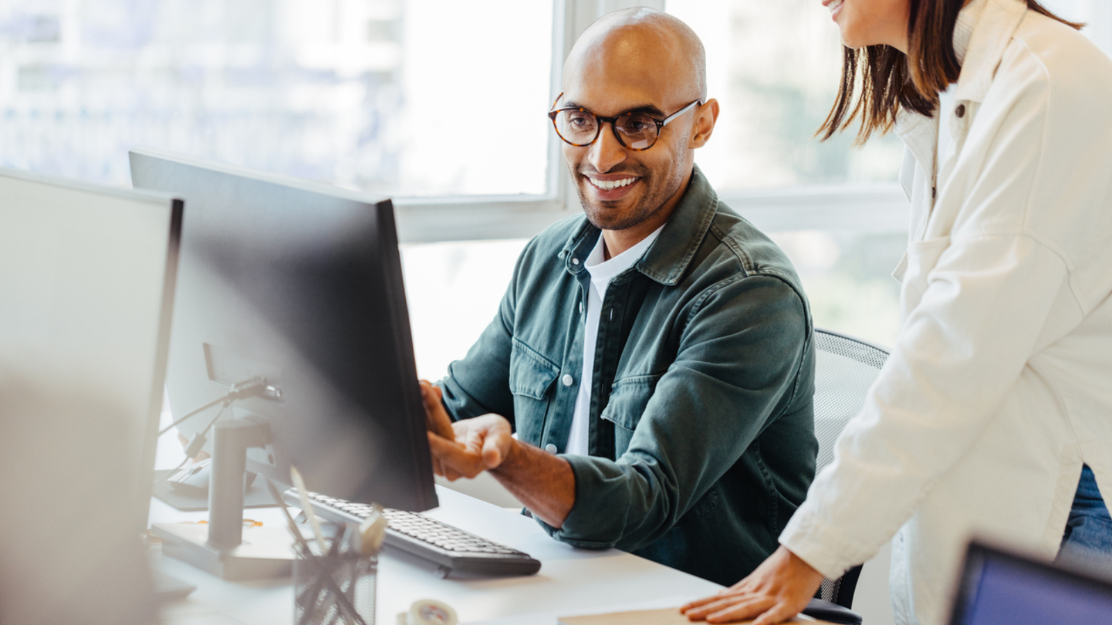 Software engineers using a computer and having a discussion in an office. Two creative business people working on a new coding project together.