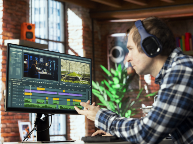 Freelancing video editor in home office wearing headphones to polish raw footage and improve audio quality. Videographer professionally adjusting clips, applying sound effects to film
