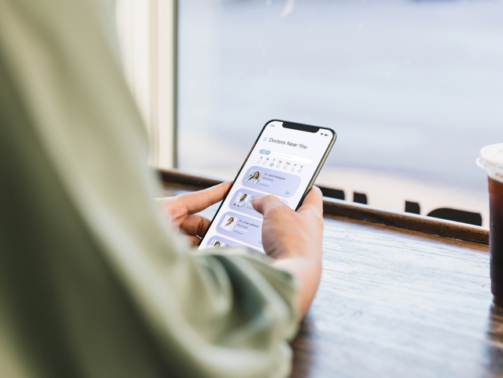 Sitting at a coffee shop, and unrecognizable young adult woman surfs the net for a new doctor.