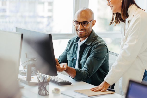Software engineers using a computer and having a discussion in an office. Two creative business people working on a new coding project together.