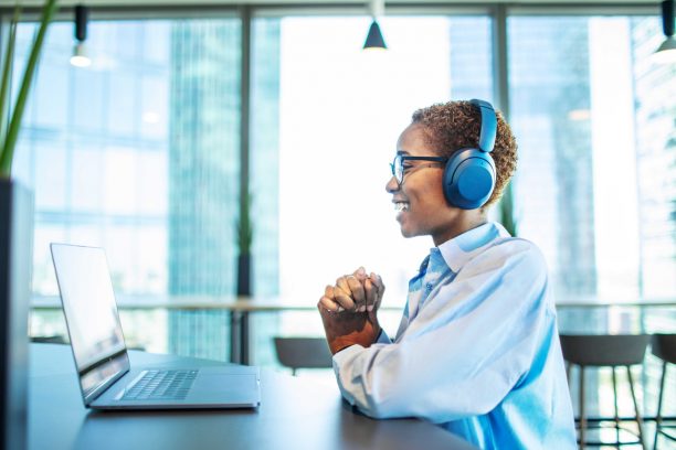 Young adult Black woman having job interview online using laptop in modern coworking