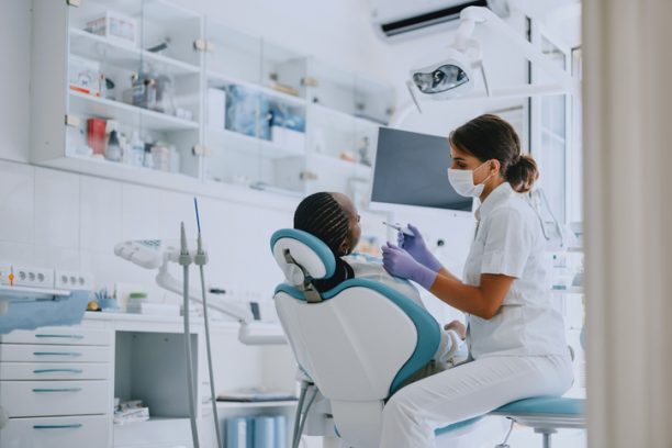 Dentist examining a patient in a modern dental clinic. Professional dental care and hygiene practice.