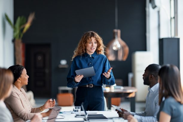Confident businesswoman presents to a diverse team during a collaborative meeting in a stylish office environment, promoting teamwork and communication.