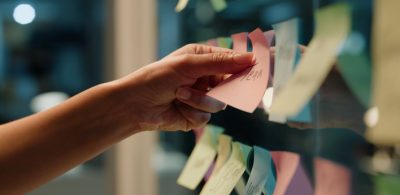 Hand, business and sticky note with planning, ideas and creativity for novel and schedule for writing.